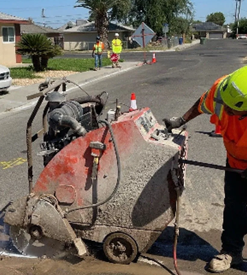 Worker operating a high-pressure pipe jetting machine on a residential street, with safety gear and traffic cones visible, illustrating Nor-Cal Pipeline Services' effective utility maintenance solutions.