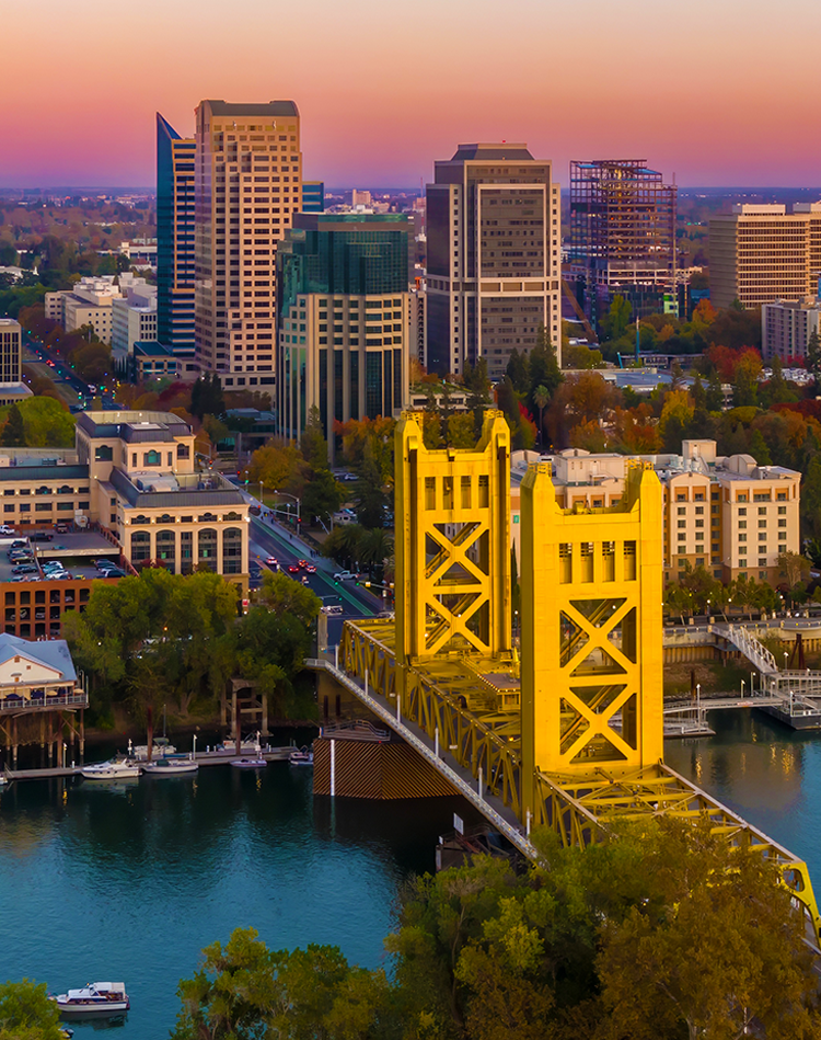 Sacramento skyline featuring the iconic yellow Tower Bridge at sunset, showcasing urban infrastructure and the Sacramento River.