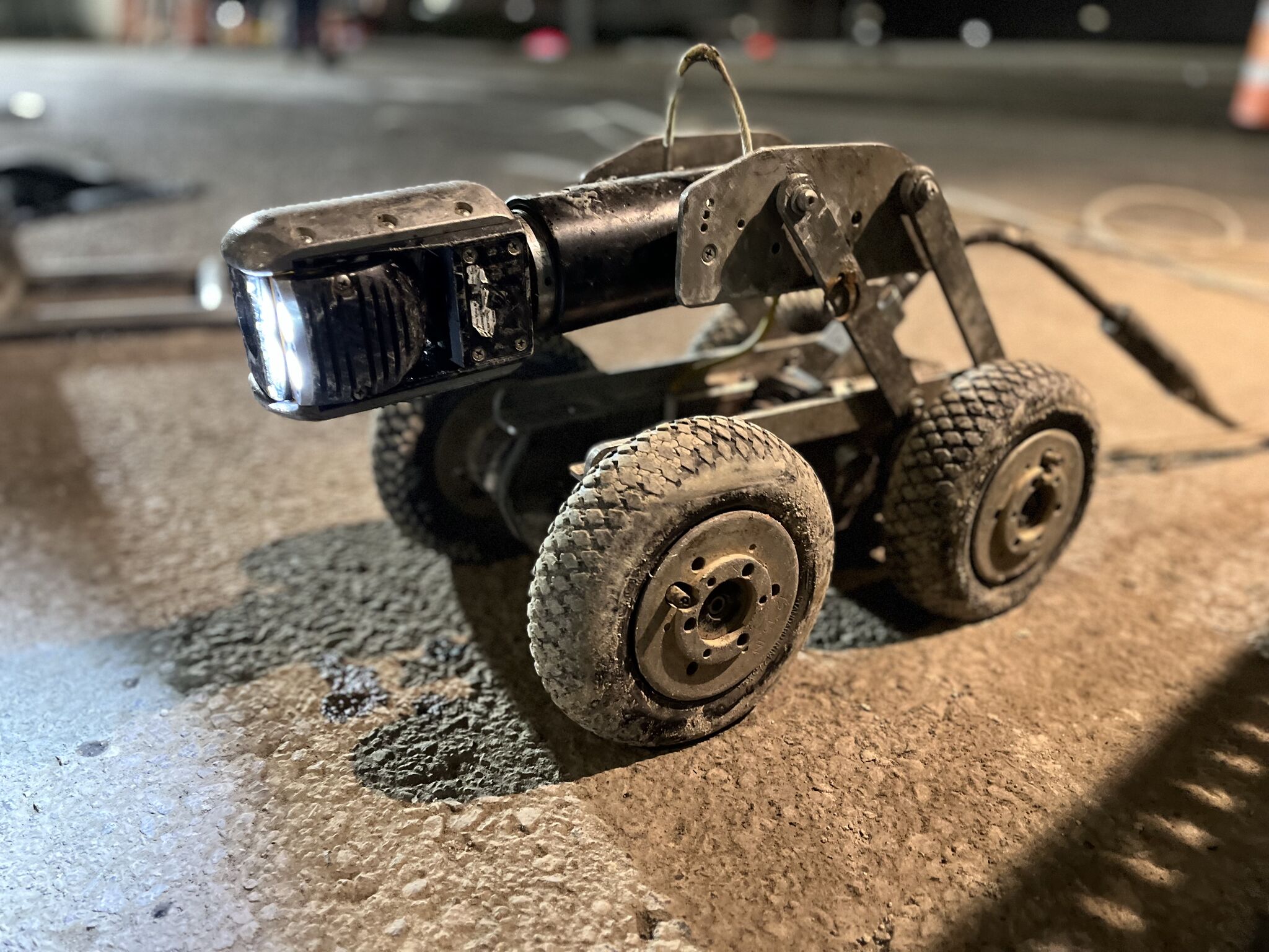 1738820453454 Utility inspection robot with a light, designed for underground utility services, positioned on a surface, showcasing Nor-Cal Pipeline Services' advanced technology in sewer maintenance and hydro excavation.
